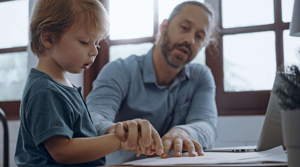 A father and young child drawing together at a table, symbolizing the loving bond and the importance of fathers' equal custody rights in Iowa.
