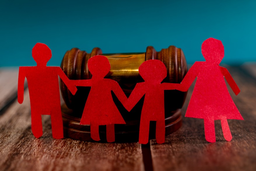 Paper cutout figures of a family holding hands, with a gavel in the background, symbolizing family law and spousal support modification or termination in Iowa.